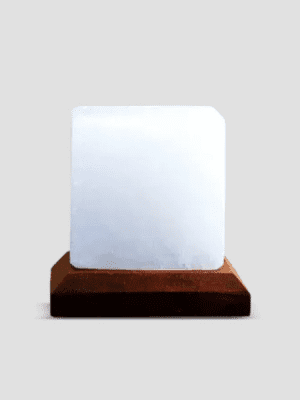 Minimalist geometric cube lamp made from rare White Himalayan Salt on a dark wood base, manufactured by Suhail Salt, a premier salt product exporter.